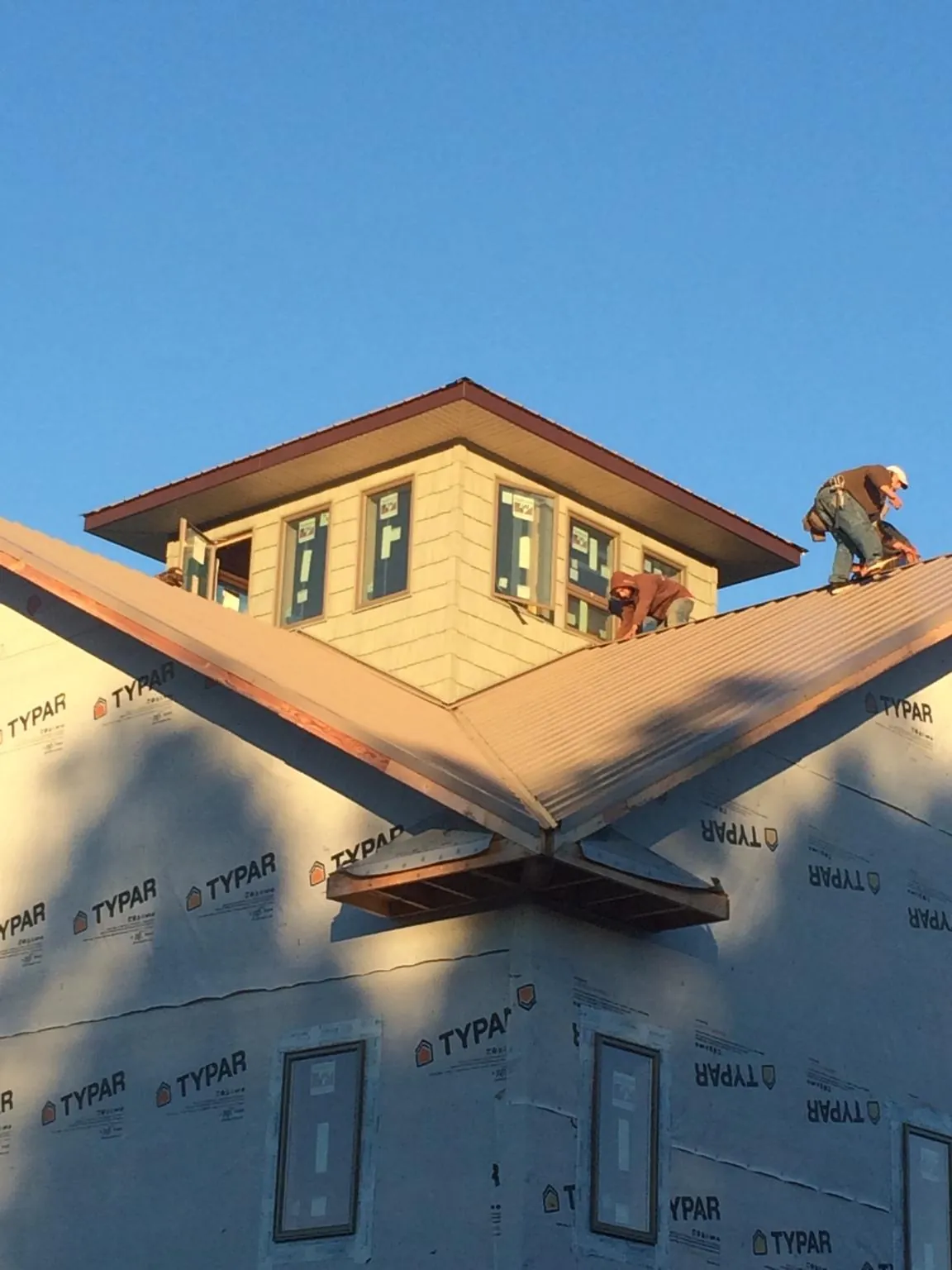 Roofers working around a rooftop cupola on a new metal roof at sunset — Roof Waterproofing in Cape May by Roofing Brothers